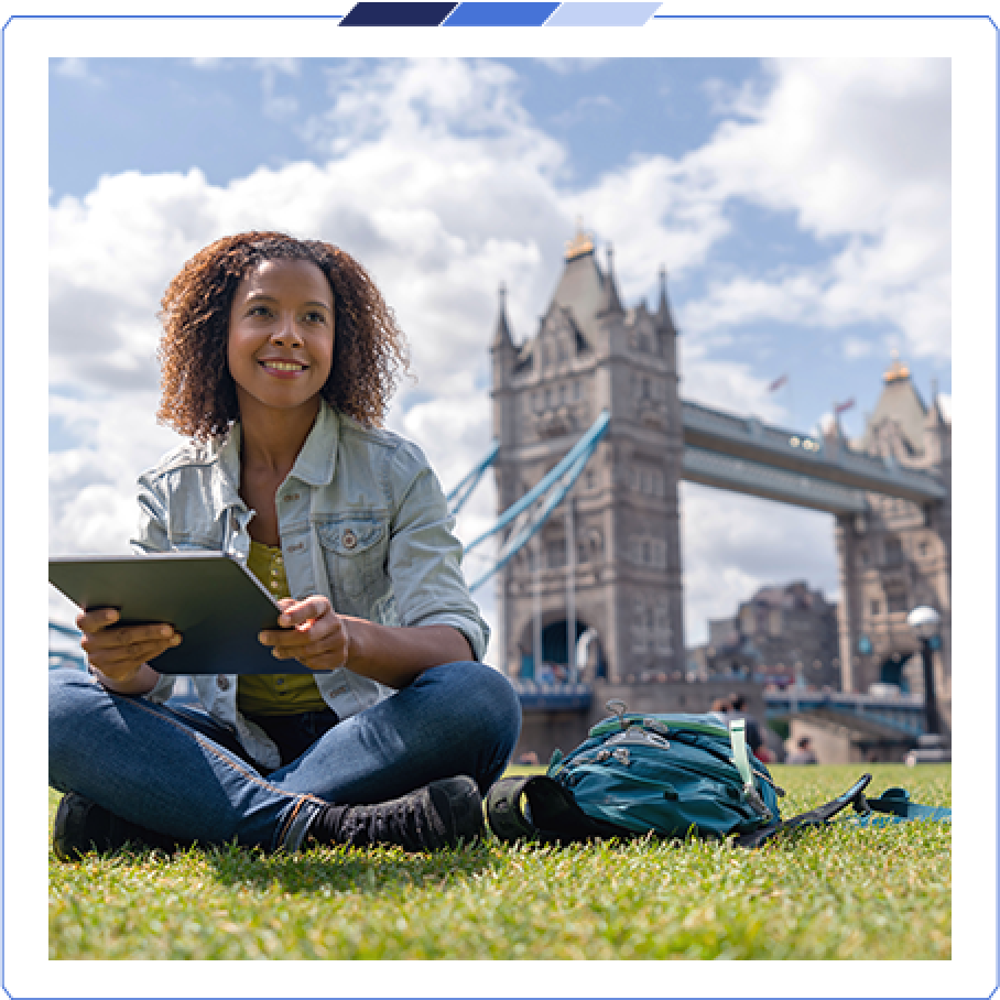 A customer sat on a field holding an iPad with the London Bridge in the background